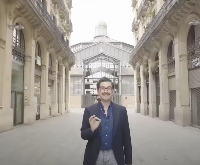 Persona presentando frente a edificio histórico con arquitectura modernista, ideal para contenido institucional o inmobiliario